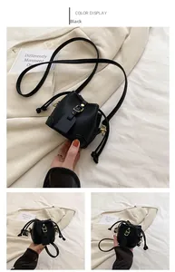 Detail of black litchi grain leather mini bucket bag with gold metal clasp and drawstring