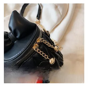 Gros plan du mini sac matelassé noir avec nœud décoratif et chaîne en métal doré