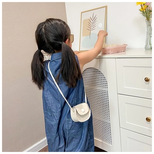 Detail of a creamy white crocodile pattern mini crossbody bag worn by a young child