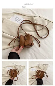 Detailed view of the brown mini drawstring bucket bag with litchi texture and slim strap