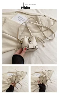 Detail of white mini bucket bag featuring lychee texture leather and gold metal buckle