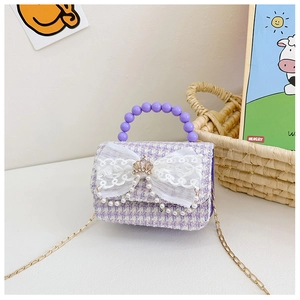Dettaglio della mini borsa in tweed con fiocco di pizzo, corona d'oro e nappe di perle