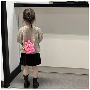 Pink quilted mini bucket bag with bow detail shown on a child model for size reference