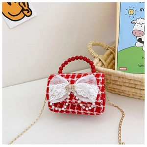 Dettaglio borsa bimba in tweed rosso con manico di perle, fiocco e coroncina