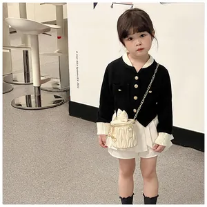 Detail of girls' black tweed style cardigan with gold buttons and cream chain bucket bag
