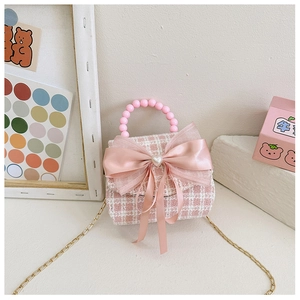 Détail du sac en tweed rose à carreaux avec nœud satiné, perle cœur et anse perles