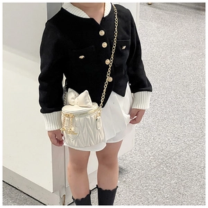 Detailed view of kids white quilted bucket bag with bow decoration and gold heart charm