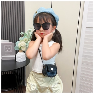 Detail of a mini black crocodile texture saddle bag on a young girl model as a crossbody accessory