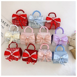 Vue à plat de mini sacs en tweed pour filles avec nœuds et poignées en perles