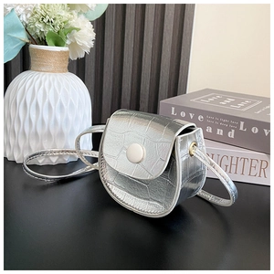 Detail showing silver crocodile-embossed mini saddle bag with white round button clasp