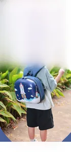 Child wearing dark blue rocket theme hardshell backpack in an outdoor park setting