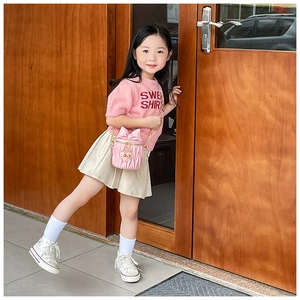 Detailed view of pink pleated bucket bag with bow and gold chain on young girl