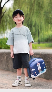 Toddler blue hardshell backpack with cartoon rocket and space design held by a boy