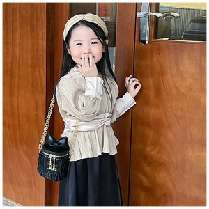 Girl's beige pleated top and black skirt with quilted bow bucket bag and gold chain