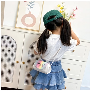 Detail of white kitten shoulder bag with rainbow ears worn by a child in home setting