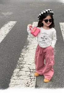Fashionable young girl in white t-shirt and pink cargo pants with a matching mini handbag