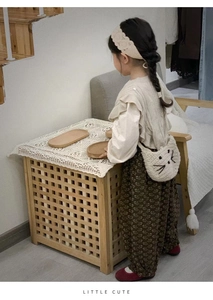 Toddler girl modeling a crochet cat bag with lace blouse and floral pants in cozy indoor setting