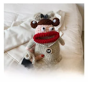 Detail of crochet doll bag featuring big red lips and pearl necklace accessories