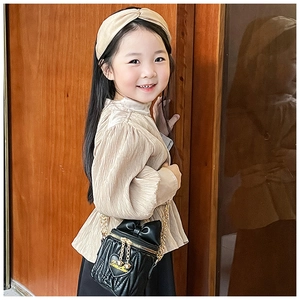Close-up of children's black quilted crossbody bag with heart detail and gold chain