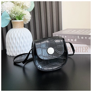 Detail of black crocodile texture mini saddle bag with white round snap button closure