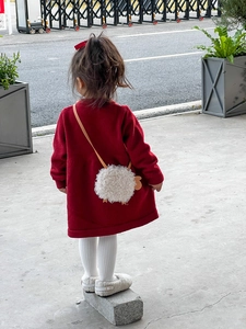 Détail d'un joli sac à bandoulière en agneau pelucheux avec une veste en tricot rouge