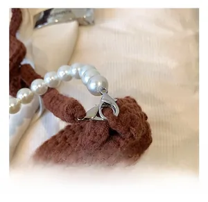 Detail of dark brown crochet bag featuring white pearl strap and silver lobster clasp hook