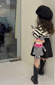 Detail of crochet sausage mouth doll bag with grey knit texture and pink bow decoration