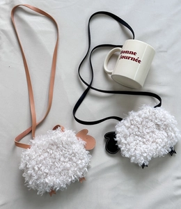 Détail de sacs bandoulière agneau en peluche avec finitions en cuir rose et noir contrasté