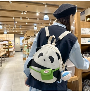 Detail of cute panda backpack featuring green pocket and blue cloud charm on a strap