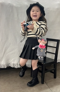 Detailed view of child model wearing a funny crochet doll bag with pink lips and grey dress
