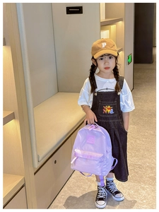 Detailansicht eines lila Kleinkind-Rucksacks mit Logo-Patch an einem Kindermodell
