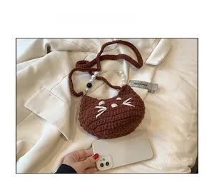 Brown crochet cat bag with pearl handle shown next to phone for size comparison