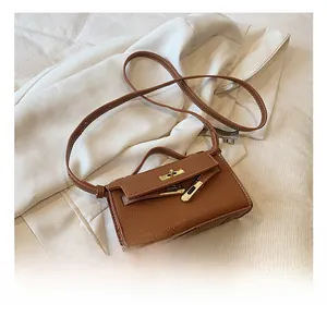 Macro detail of brown litchi grain leather bag with gold metal buckle and handle
