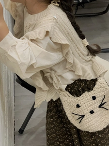 Detail of a handmade cat-shaped crochet shoulder bag with pearl handle on a girl's outfit