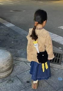 Outdoor street shot of a cute handmade ostrich crochet crossbody bag for kids