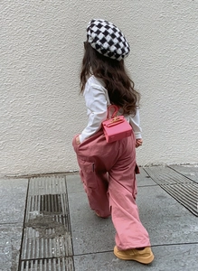 Outdoor shot of a girl wearing a pink mini handbag and a checkered beret outfit