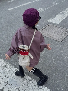 Close-up of a handmade crochet cartoon crossbody bag with thick knit hat and leather jacket
