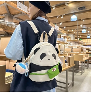Detail of cute panda backpack featuring a plush doll charm and a mini green bag accessory