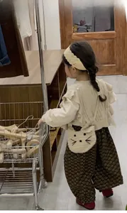 Rear view of a girl wearing a crochet cat crossbody bag with a retro floral outfit