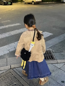 Detail of cute ostrich crochet crossbody bag with yellow legs on a child's shoulder