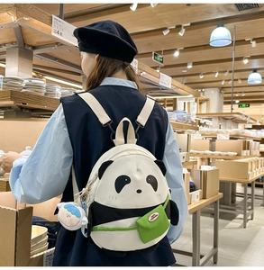 Detail of cute panda backpack with embroidery, green flap pocket and cloud charm accessory