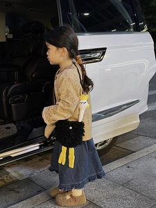 Detail of child wearing a cute black crochet ostrich bag with plush knit texture
