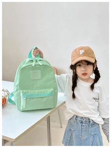 Kleines Mädchen hält einen hellgrünen Kindergartenrucksack mit Girl Cats Aufnäher-Detail