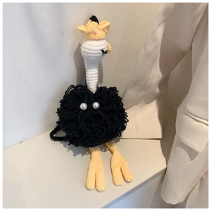 Detail showing handcrafted crochet ostrich mini bag with pearls and yellow crown