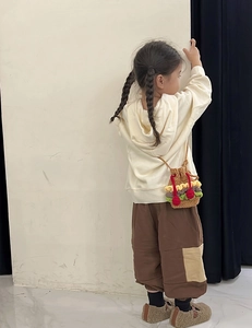 Detail of child wearing a crochet hamburger drawstring bucket bag with colorful knit layers