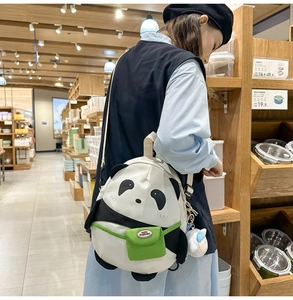 Side view of cute panda-shaped backpack with green pocket worn by model in shop