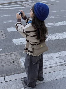 Girl modeling a khaki leather cross-body bag with litchi texture on a crosswalk