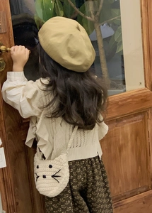 Detail of crochet cat-shaped crossbody bag on a child wearing a vintage floral dress