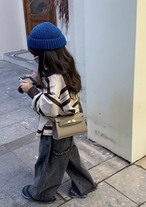 Outdoor street style view of a girl wearing a grey mini litchi pattern crossbody bag