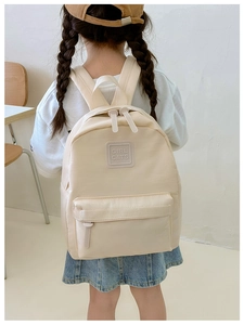 Nahaufnahme eines cremefarbenen Kleinkinderrucksacks mit 'GIRL CATS' Patch und Doppelreißverschluss